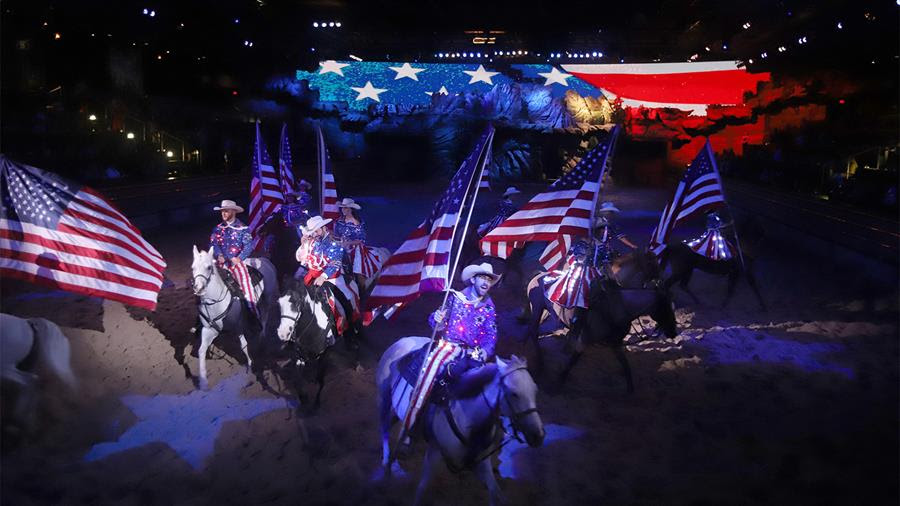 Entertainers on horses wave large American flags as part of the finale at a Dolly Parton's Stampede dinner show.