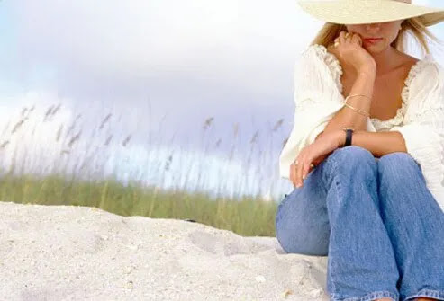 A woman with psoriasis covers up on the beach.