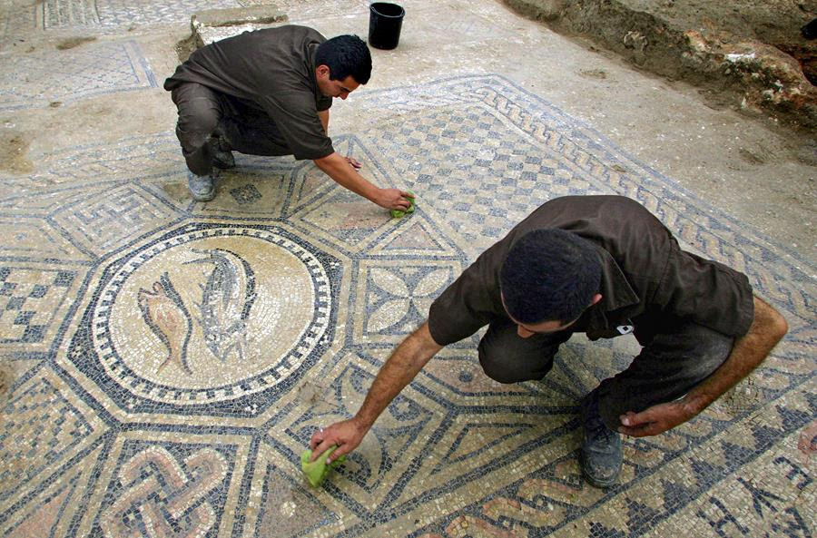 People clean an ancient tile mosaic in Israel.