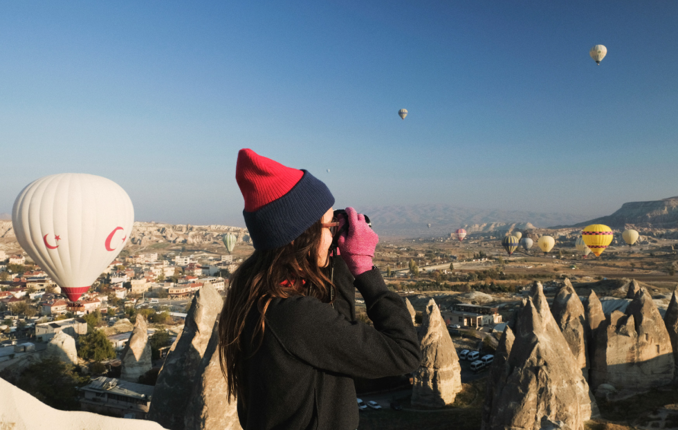 Uma mulher tira fotos de balões de ar quente em Goreme.