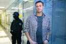 FILE- In this Dec. 26, 2019, file photo, Russian opposition leader Alexei Navalny speaks to the media in front of a security officer standing guard at the Foundation for Fighting Corruption office in Moscow, Russia. Russian authorities on Tuesday Dec. 29, 2020, ramped up pressure on top Kremlin critic Alexei Navalny, leveling new charges of fraud against him. (AP Photo/Alexander Zemlianichenko, File)