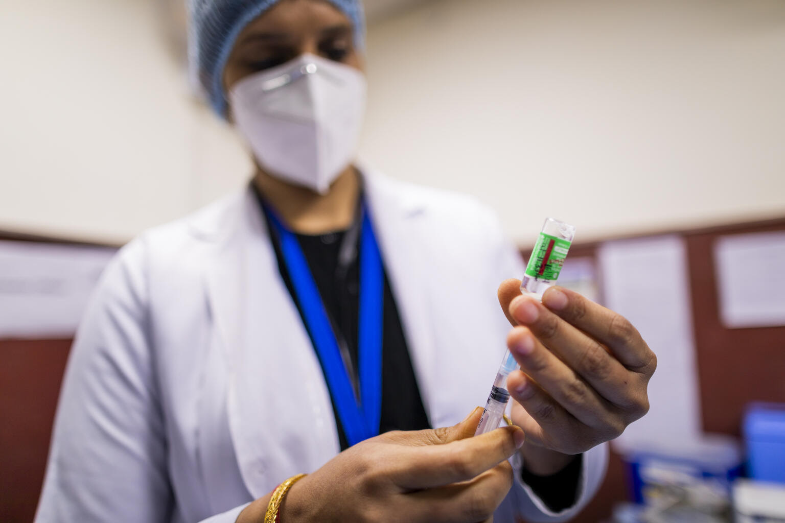 Photo of a doctor extracting medicine from a vial into a syringe.