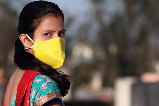 Photo of a young woman wearing a yellow face mask.