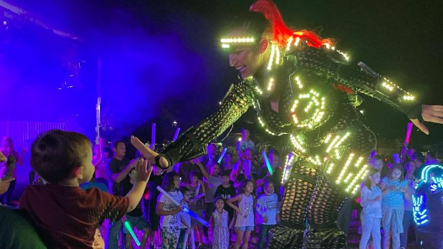 Stilt walker dancer gives a child a high five at Weston's 25th Anniversary Celebration on Dec. 11, 2021.