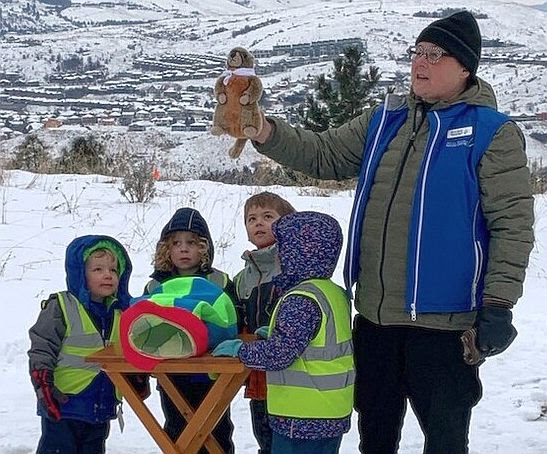 Picture of a man with a groundhog hand puppet talking to children with it.