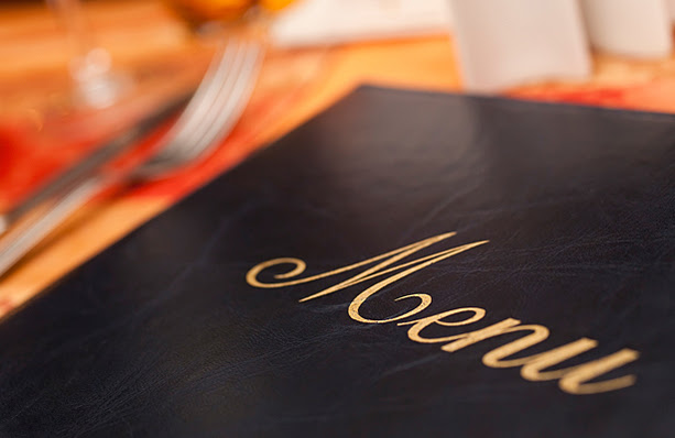 The front cover of a food menu with silverware in the background.