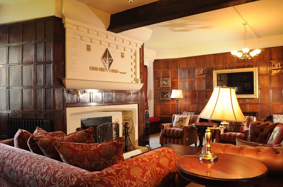 The drawing room at Happisburgh Manor features a fire and a coat of arms. There is also a huge mirror and plenty of comfortable chairs