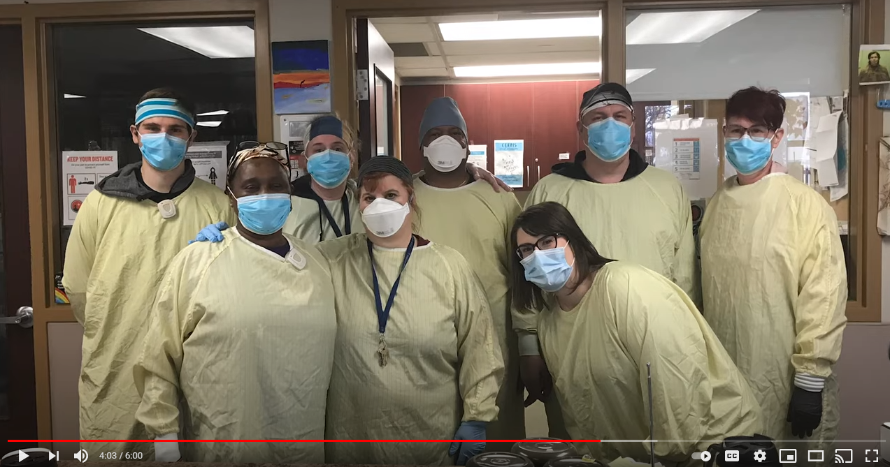 A screenshot from the music video, showing a group of masked but smiling healthcare workers.