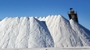 A mountain of salt against a blue sky, with a conveyor visible in the background.