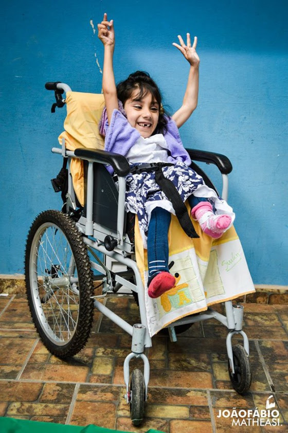 Esta foto é a Pri em sua cadeira de rodas, Pri está linda e sorridente.