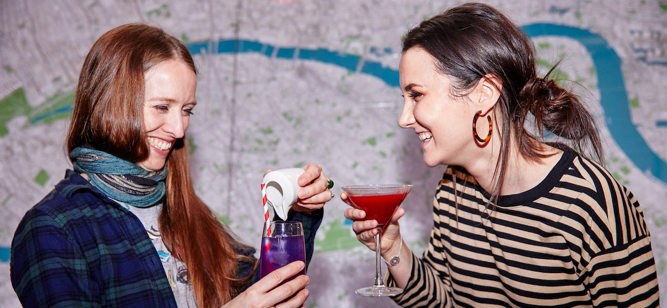 Two girls laughing and drinking cocktails at a Thursday After Dark event