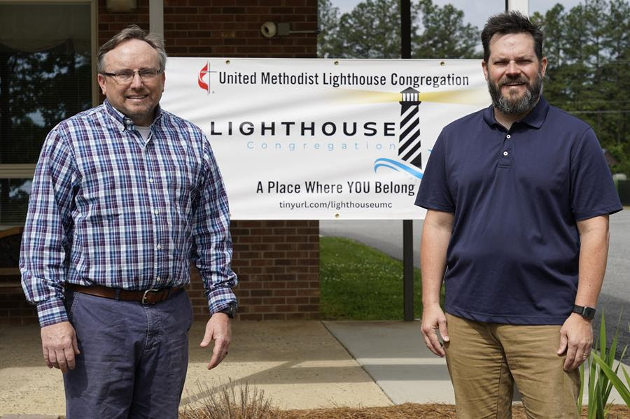The Rev. Ed McKinney, pastor of Stokesdale United Methodist Church, left, and Michael Hahn, right, pose for a photo near a welcoming sign at the church in Stokesdale, N.C.