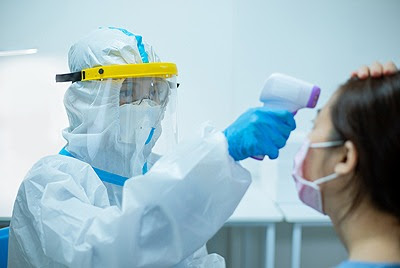 a doctor in PPE checking a patient's fever reading