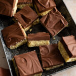 chocolate barfi recipe squares scattered on a metal tray.